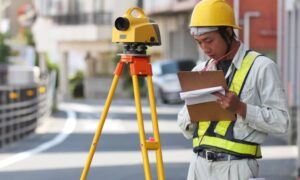 Land surveyor conducting a residential survey in a Boston neighborhood using tripod equipment