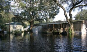 Flooded residential homes with high water levels, highlighting the importance of a Flood Elevation Survey after severe storms and flooding.