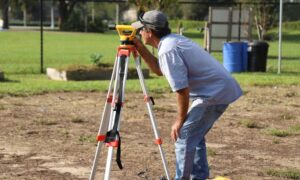 Land surveyor measuring a residential property line to assess boundary survey cost and prevent disputes