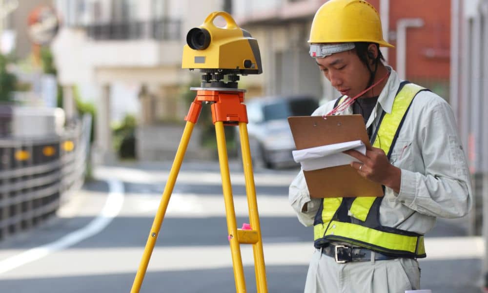 Land surveyor conducting a residential survey in a Boston neighborhood using tripod equipment