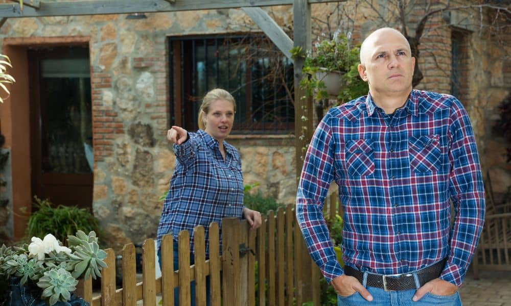 Neighbors arguing near a backyard fence during a property line survey dispute