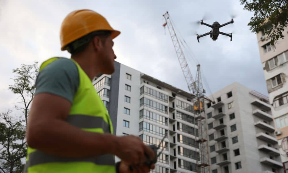 Construction drone operator at redevelopment site - ALTA SURVEY Massachusetts A worker uses a drone for aerial surveying at a redevelopment site