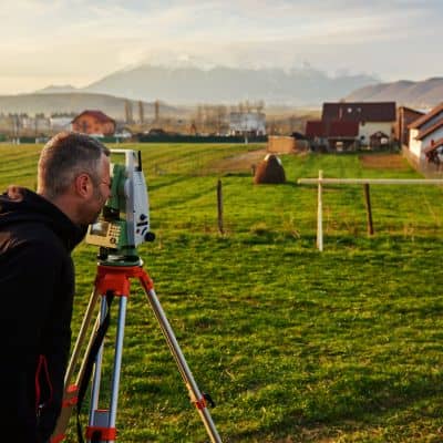 Land surveyor using measurement equipment - ALTA SURVEY Massachusetts Licensed land surveyor using professional equipment during a property line survey