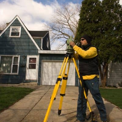 Residential land surveyor measuring home elevation - ALTA SURVEY Massachusetts Land surveyor measuring a home’s elevation for an elevation certificate to assess flood risk and insurance requirements