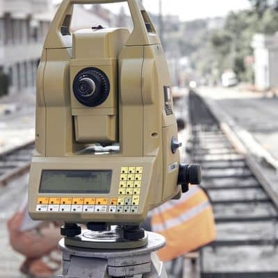 Total station instrument used for land surveying alignment and elevation verification near rail tracks