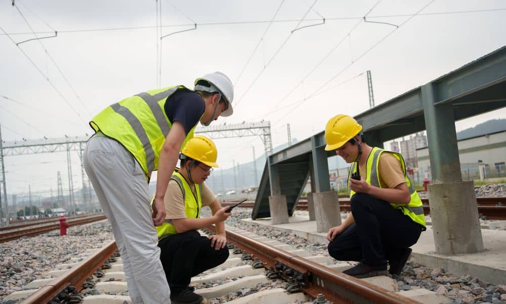 Field engineers performing land surveying checks on railway track alignment and elevation