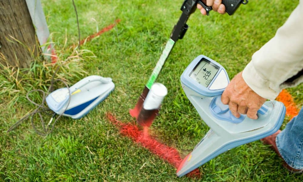 Surveyor locating a boundary marker to find property lines before installing a fence
