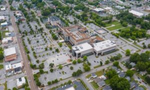 Aerial view of a mixed-use development site with buildings, parking areas, roads, and surrounding properties
